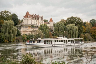 Bateau de croisière fluviale naviguant sur la Loire devant un château historique en automne
