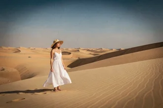 Femme en robe blanche contemplant les dunes du désert tunisien du Sahara lors d'un itinéraire touristique en Tunisie