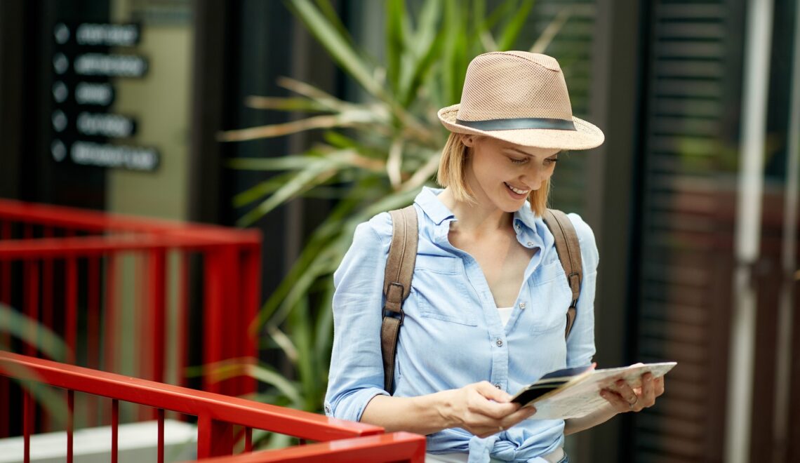 Happy woman looking at a map while exploring foreign city.