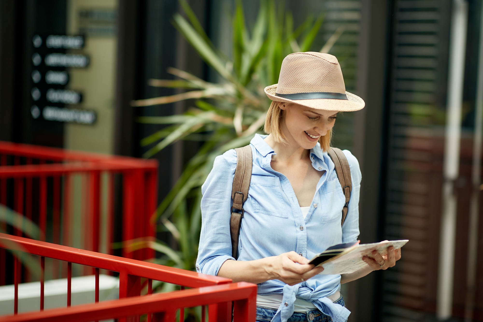 Happy woman looking at a map while exploring foreign city.